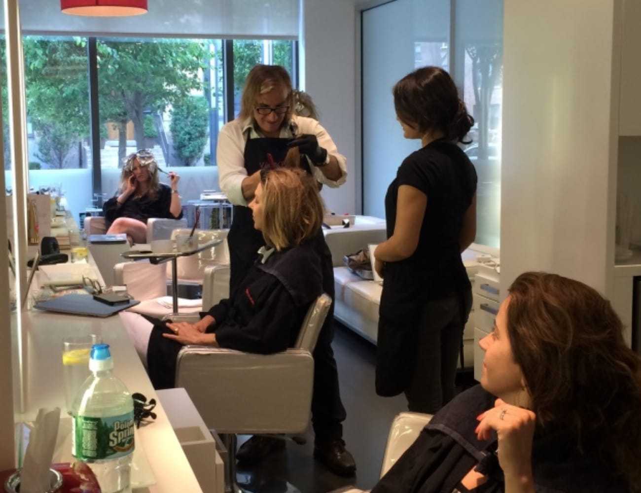 Hair salon with stylists attending to clients in modern, bright setting.