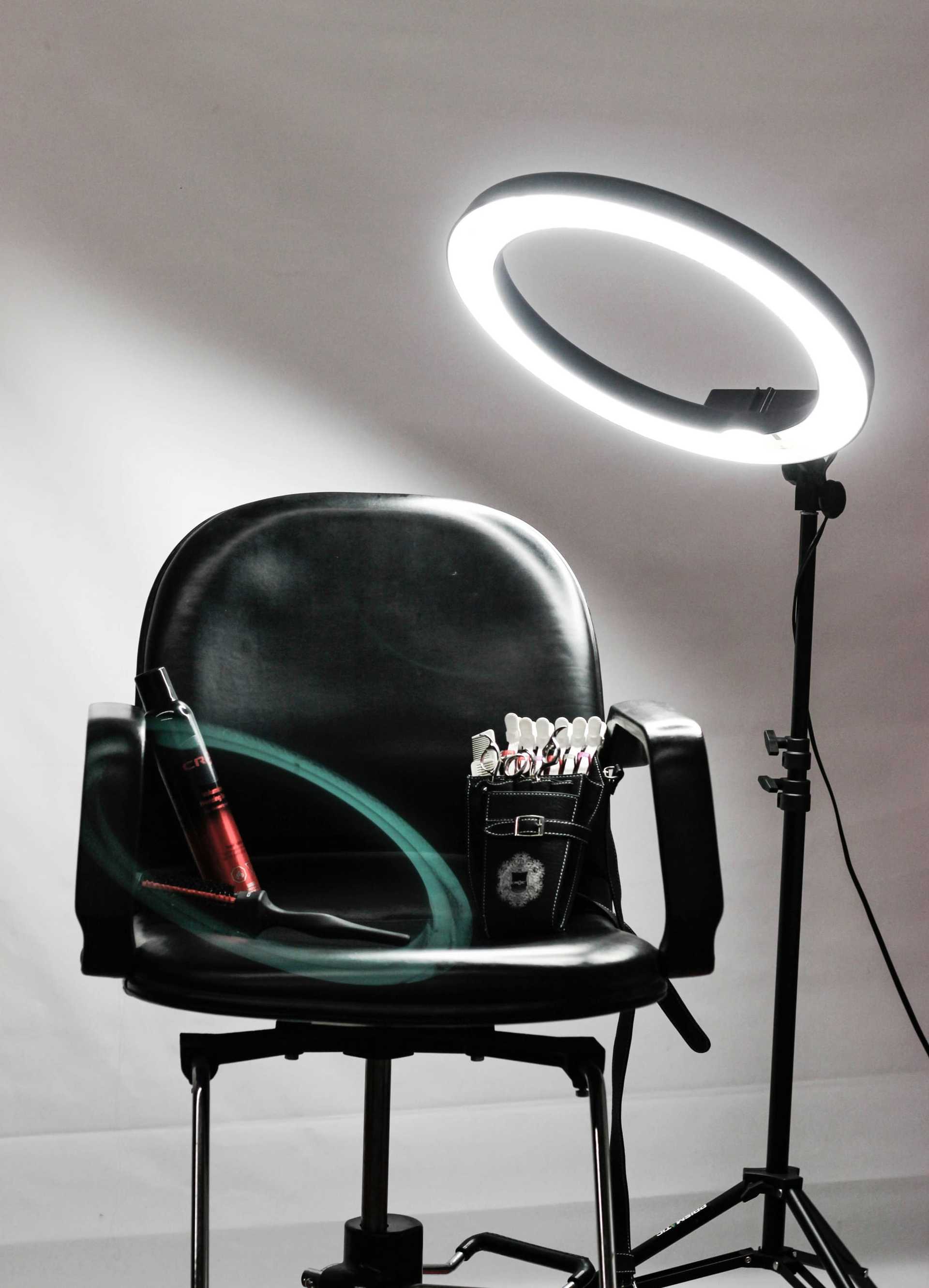 Salon chair with hair spray, a tool organizer, and a bright ring light setup.